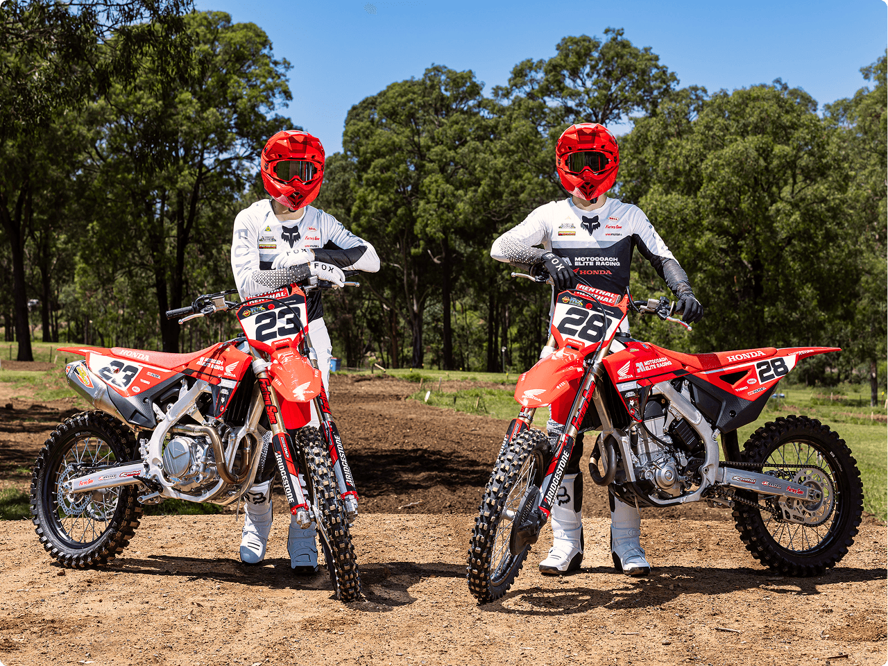 Two Motocoach Elite Racing riders standing with their Honda motocross bikes, numbers 23 and 28