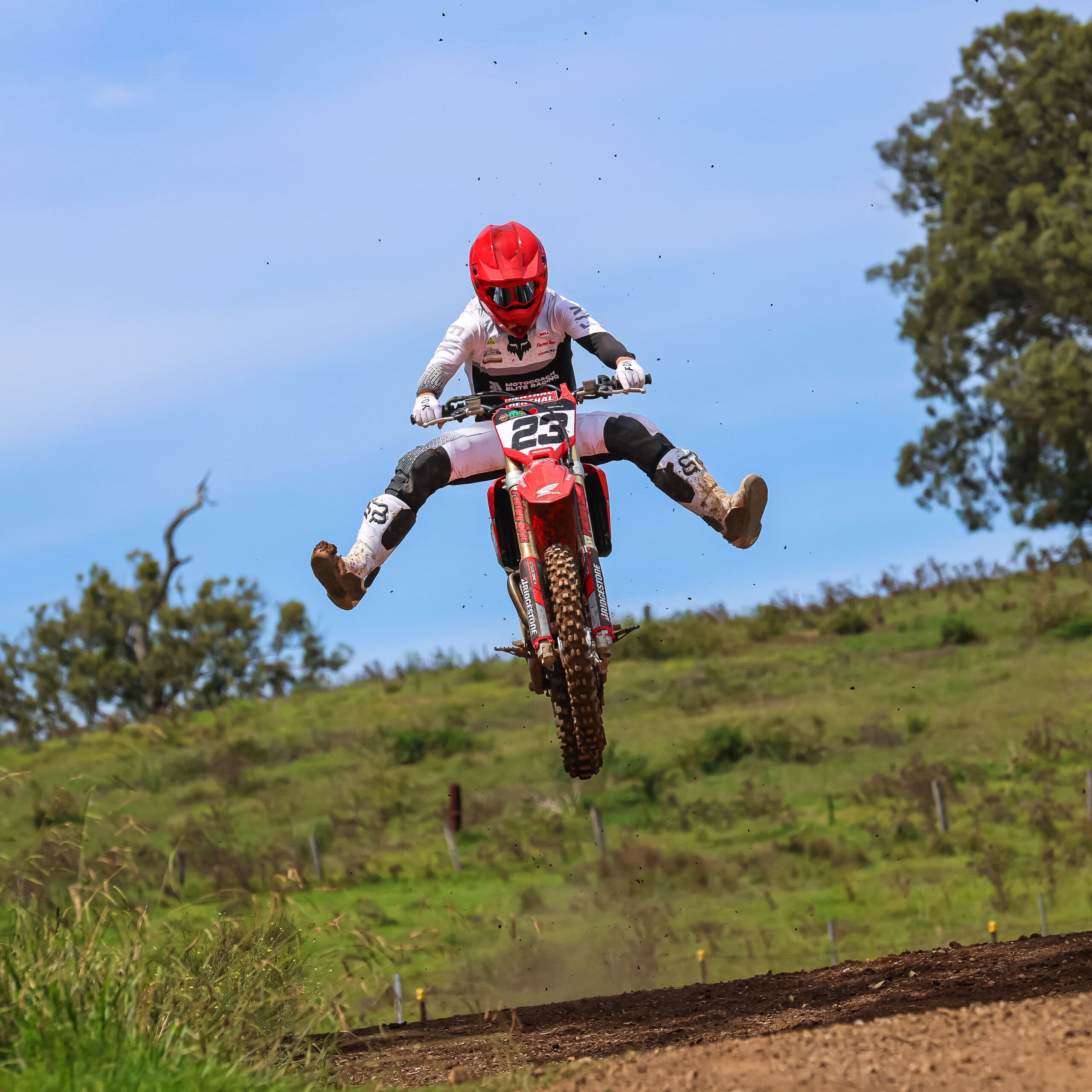 Motocoach Elite Racing rider kicking both legs out mid-jump on a Honda motocross bike