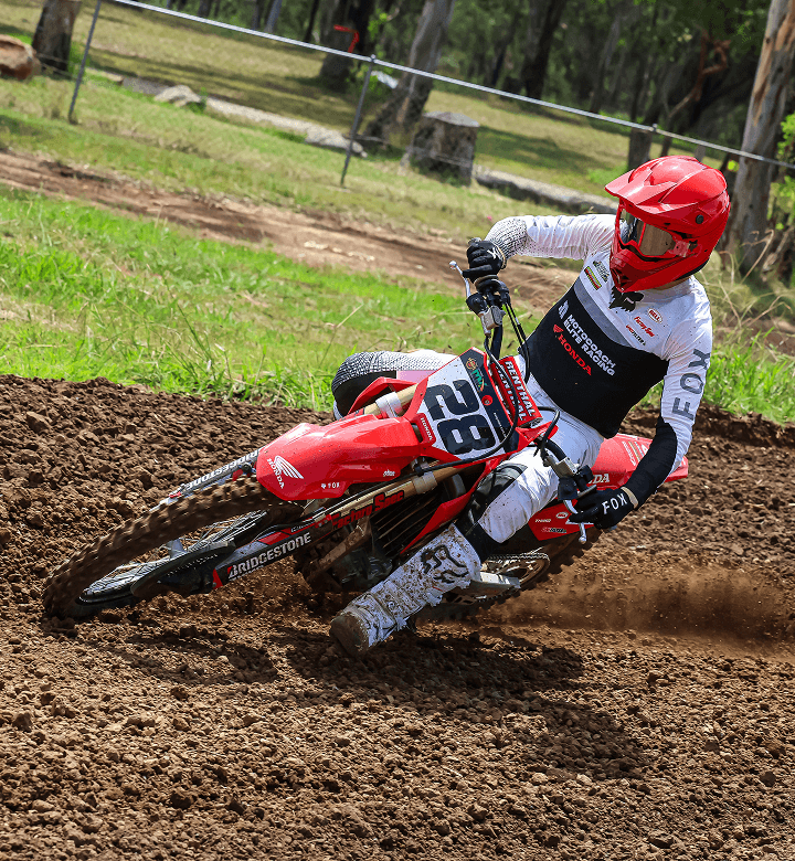 Motocoach Elite Racing rider leaning a Honda through a dirt corner, number 28