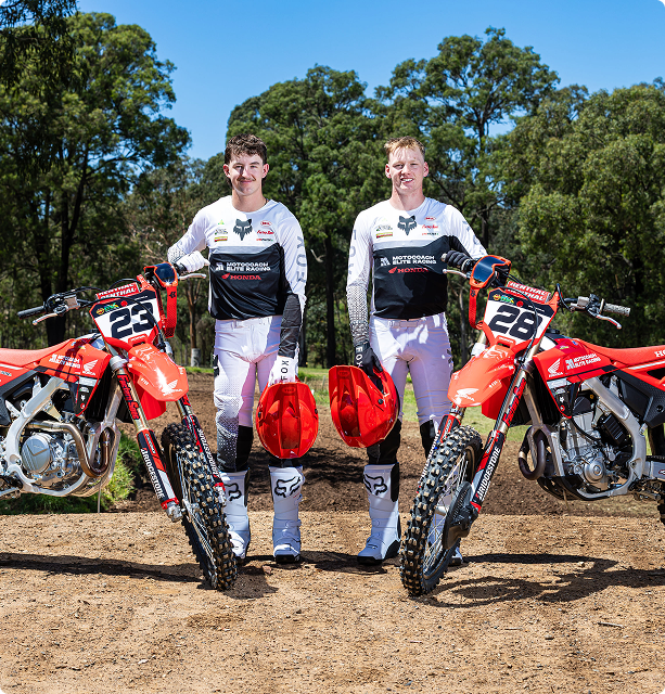 Two Motocoach Elite Racing riders in team kit standing beside their Honda race bikes